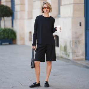 PARIS, FRANCE - MARCH 9: Laura Wittek is seen wearing a black long sleeve top with a relaxed, slightly oversized fit from Uniqlo; black knee length shorts with a minimal silhouette from Amazon Fashion; black leather loafers with a classic slip on design from Liviana Conti; a black leather Balenciaga called "Lindsay Medium Shoulder Bag" with a soft, structured shape; slim rectangular sunglasses with a narrow frame and warm tinted lenses from Bridge Eyewear; she is holding a takeaway coffee cup; an Apple iPhone Pro Max in Cosmic Orange; silver jewelry from COS, including hoop earrings, multiple rings; natural make-up; natural nails; her blonde hair is worn in a short, slightly tousled bob with a natural finish during Day Eight of Paris Fashion Week - Womenswear Fall/Winter 2026/2027 on March 9, 2026 in Paris, France. (Photo by Moritz Scholz/Getty Images)