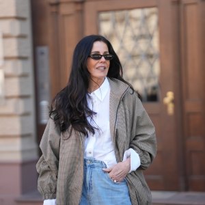 Angelika Hanel is seen wearing an oversized camel brown „Baxter“ bomber jacket in a micro houndstooth check pattern with a zip fastening, dropped shoulders, wide elasticated hem and cuffs and a voluminous silhouette from The Frankie Shop; a white classic button down shirt with a point collar and wide statement cuffs visible at the sleeves from Zara; light blue wide leg barrel fit jeans from Zara; slim oval acetate sunglasses with a narrow black frame and dark tinted lenses from H&M; a natural manicure; small golden hoop earrings; her long dark brown hair is worn loose and wavy with a center part; with a natural make up look on April 22, 2026 in Frankfurt am Main, Germany.