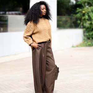 LONDON, ENGLAND - SEPTEMBER 18: Nadine Petzke is seen wearing a camel cable knit sweater over a dark brown high neck layer; tailored dark brown wide leg trousers with a black leather belt; black leather square toe flats; wearing gold hoop earrings and stacked bracelets; voluminous natural curly hair worn loose outside the Marks & Spencer show during London Fashion Week September 2026 on September 18, 2026 in London, England. (Photo by Moritz Scholz/Getty Images)