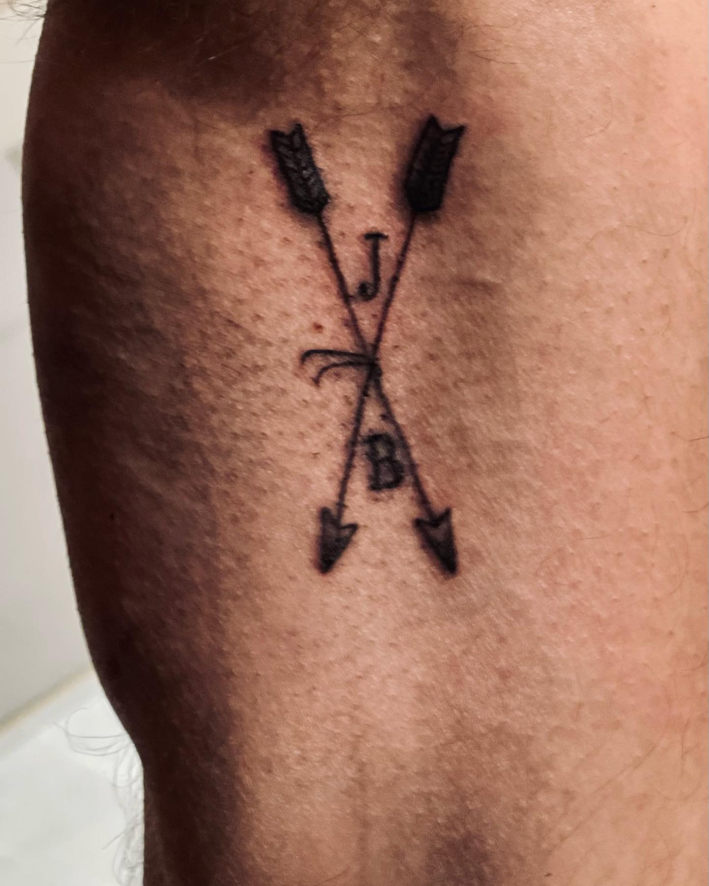 Fine line arrow tattoo on the inner forearm.