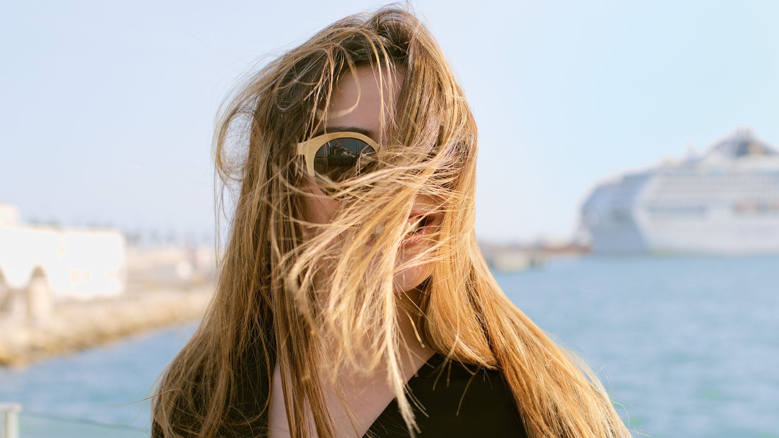 Head portrait of a beautiful young woman with her hair blown by the wind in front of the sea