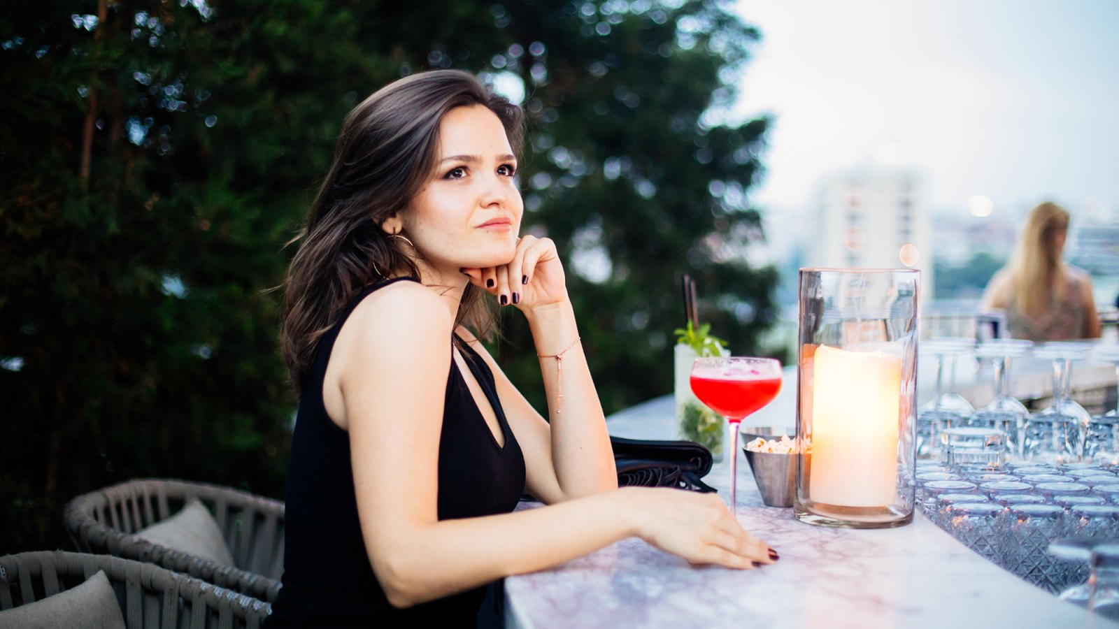Beautiful woman drinking pink cocktail at roof bar