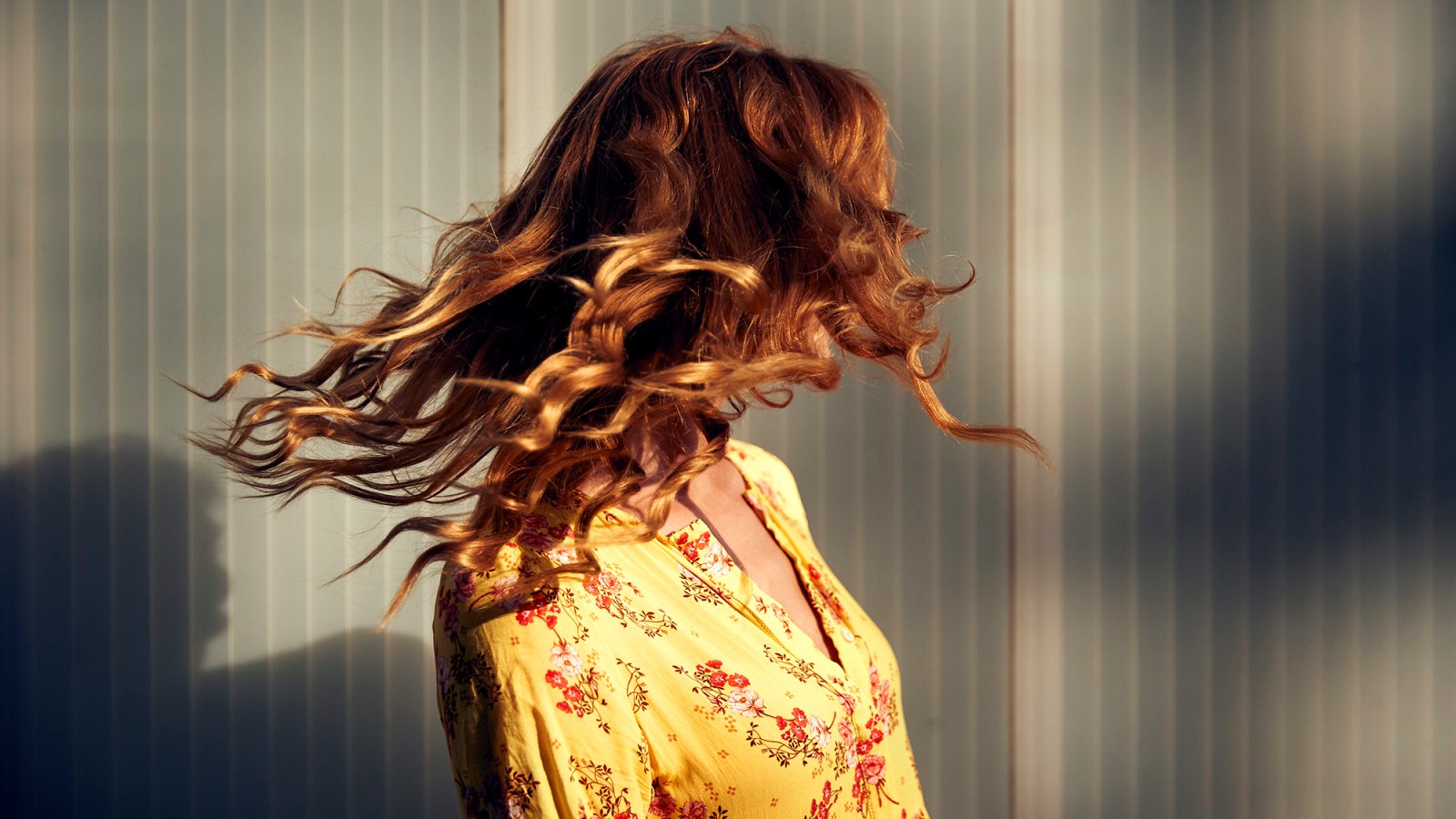 Red-haired woman throwing her hair in the evening sun
