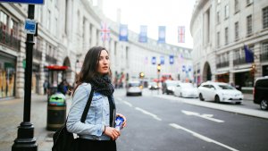 Young woman walking on the streets of central London, wearing a denim jacket and a scarf.