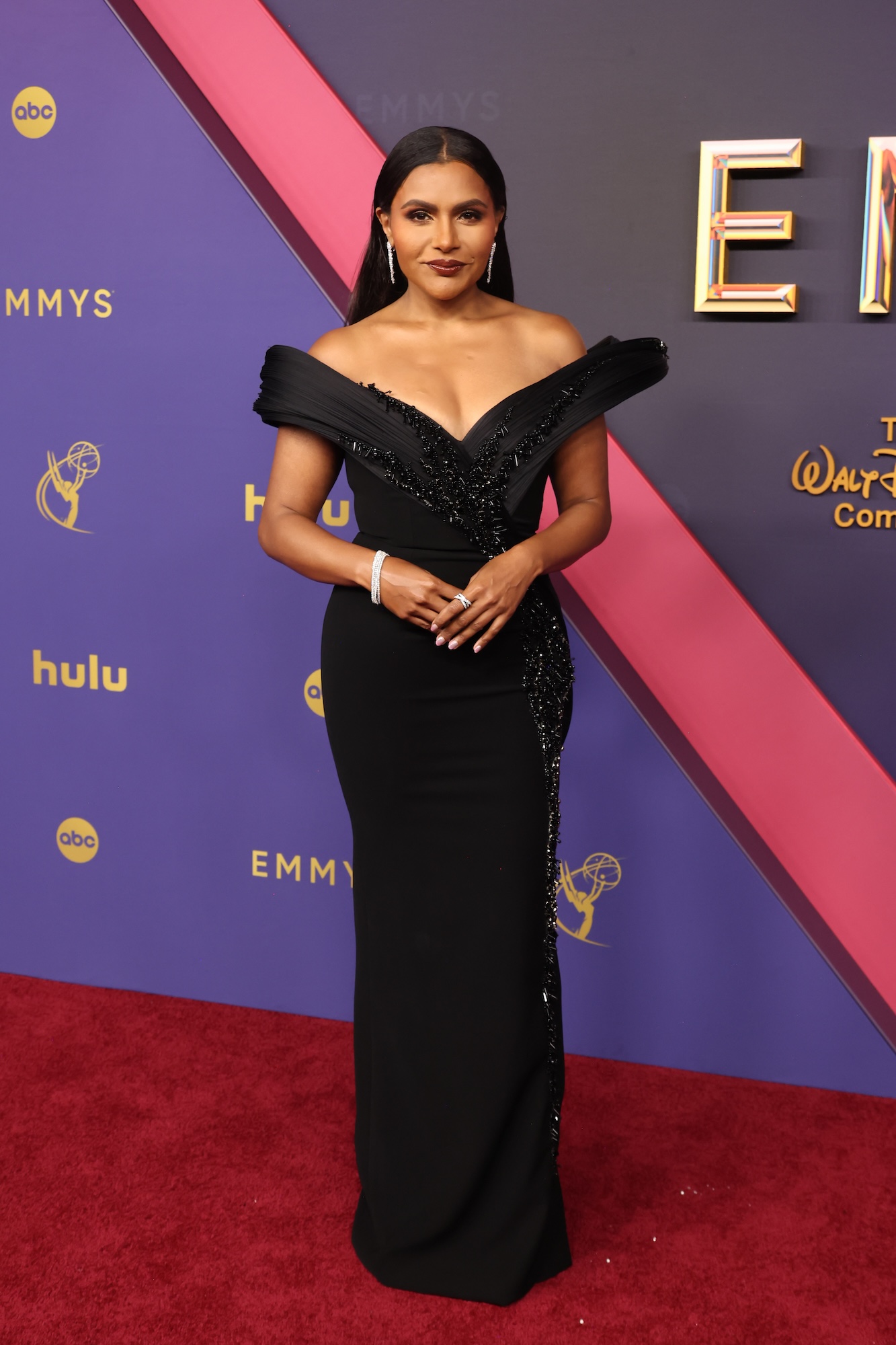 Mindy Kaling luce elegante con un vestido negro estructural en la alfombra roja de los Emmy 2024