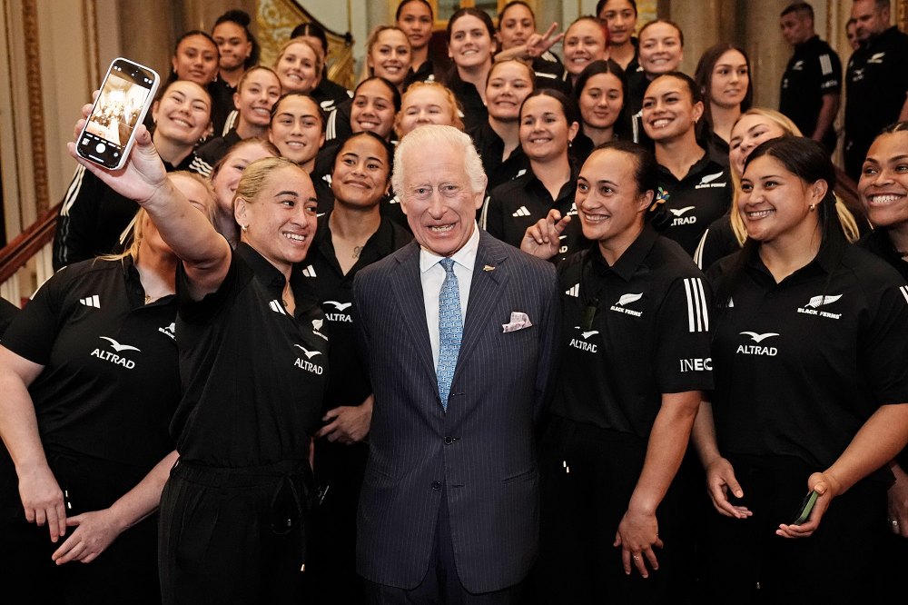 El rey Carlos III sonríe al recibir un abrazo curativo del equipo de rugby de Nueva Zelanda