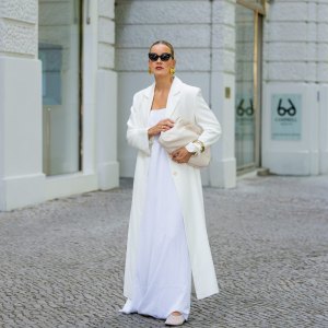 BERLIN, GERMANY - JULY 05: Tina Haase wears Gant white Maxi coat, Nakd white maxi dress, Arket mesh flats, Arket cream leather clutch bag, Joseph black Cateye Sunglasses on July 05, 2025 in Berlin, Germany. (Photo by Christian Vierig/Getty Images)