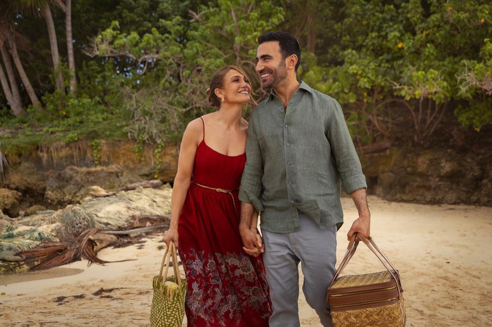 Jennifer Lopez and Brett Goldstein smiling together on a beach in "Office Romance."