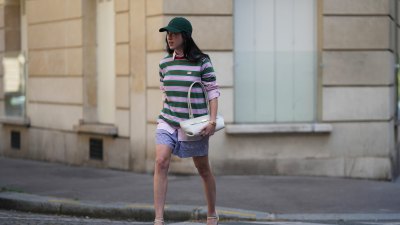 PARIS, FRANCE - JUNE 16: Anto Massoni wears a dark green cap hat by Polo Ralph Lauren, long straight dark brown hair, a green and pink striped t-shirt by Balzac Paris, a pink and white striped shirt by Figaret Paris, blue and white striped pyjama shorts by Polo Ralph Lauren, a white shoulder bag by DeMellier New York, white strappy sandals shoes by Anonymous Copenhagen, during a street style fashion photo session, on June 16, 2026 in Paris, France. (Photo by Edward Berthelot/Getty Images)