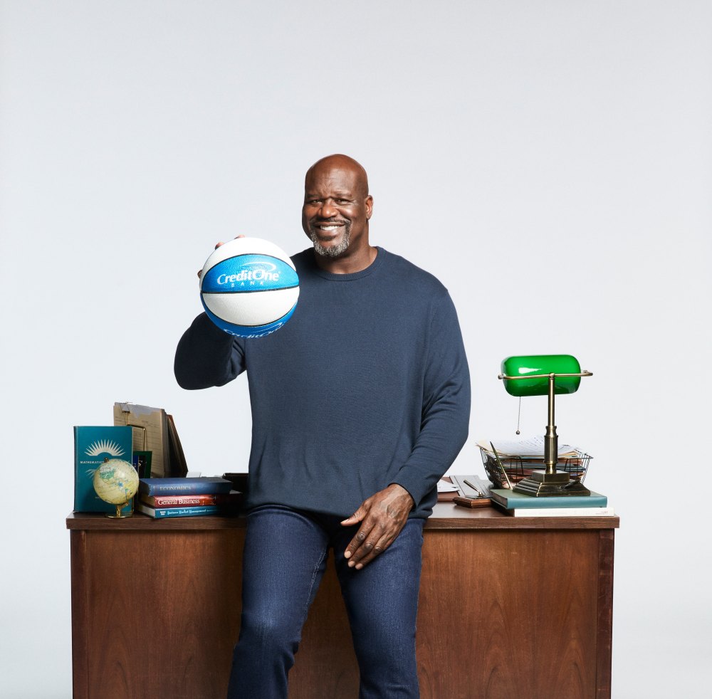 Shaq in front of a school desk holding a basketball